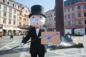 Monopoly Edition Mainz: Das Maskottchen des Spiels mit Spielepackung auf dem Mainzer Markt. - Foto:  Polar 1