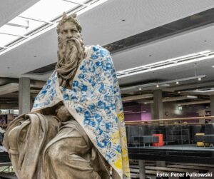 Moses-Statue mit einer Flagge mit Handabdrücken in den Farben der Ukraine in einer Bibliothek an der Johannes-Gutenberg-Universität Mainz. - Foto: Peter Pulkowski/ JGU