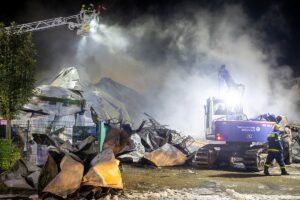 Die rauchenden Ruinen der Halle in der Nacht, rechts ein Bagger des THW. - Foto: Feuerwehr Mainz