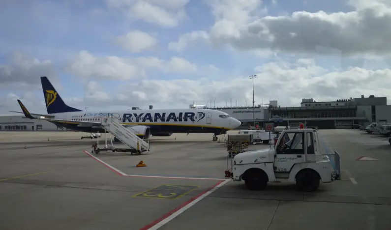 Eine Ryanair-Maschine steht auf dem Flughafen Frankfurt-Hahn vor dem Flughafen-Gebäude, im Vordergrund ein Rollfeldwagen