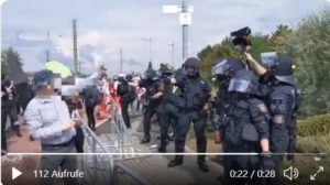 Ein Polizist sprüht Pfefferspray auf einen Demonstranten, der einen Zettel hochhält. Szene aus einem auf Twitter verbreiteten Video. - Screenshot: gik