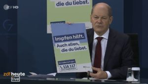 Bundeskanzler Olaf Scholz (SPD) mit einem Plakat der neuen Impfkampagne des Bundes. - Foto: gik