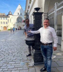 Die Freien Wähler Stephan Wefelscheid (vorne) und Christian Altmaier mit einem stillgelegten Trinkwasserbrunnen in Koblenz. - Foto: Freie Wähler