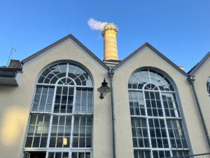 Fassade des Kesselhauses mit den typischen großen Fenstern, den Originallampen sowie dem Schornstein - das Kesselhaus ist bis heute die Heizungszentrale der Mainzer Unimedizin. - Foto: gik