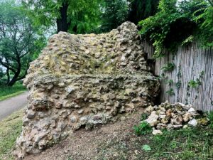 An dieser Stelle wurde der Römerstein direkt in den Gartenzaun eines Anwohners integriert, vorne rechts ein Steinhaufen, womöglich von dem antiken Pfeiler. - Foto: gik