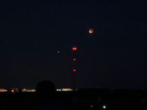 Ein glutroter Mond hängt über den Windrädern bei Klein-Winternheim: Die totale Mondfinsternis am Sonntagabend zog viele Schaulustige ins Freie. - Foto: fik