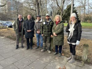 Die Obere Zahlbacher Straße im selben Areal heute: Parken zwischen Bäumen nicht mehr erlaubt, Autos auf der Straße. Das Bild stammt von der Pressekonferenz der Stadt Mainz vor Ort mit Umweltdezernentin Janina Steinkrüger (Grüne, 2. von rechts.). - Foto: Stadt Mainz  