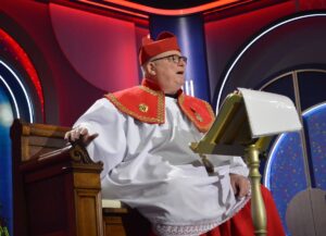 Der Obermessdiener sitzend auf der Bühne: Andreas Schmitt teilt scharf und nachdenklich aus. - Foto: gik 