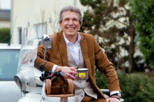 Einzelhändler Jan Sebastian tritt für die FDP an - mit Elektroroller und Kaffeetasse. - Foto: FDP Mainz