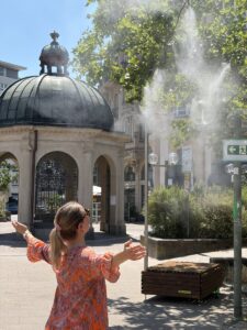 Erfrischung, Marsch! Abkühlung an der Sprühnebelanlage am Kochbrunnen in Wiesbaden. - Foto: Stadt Wiesbaden 